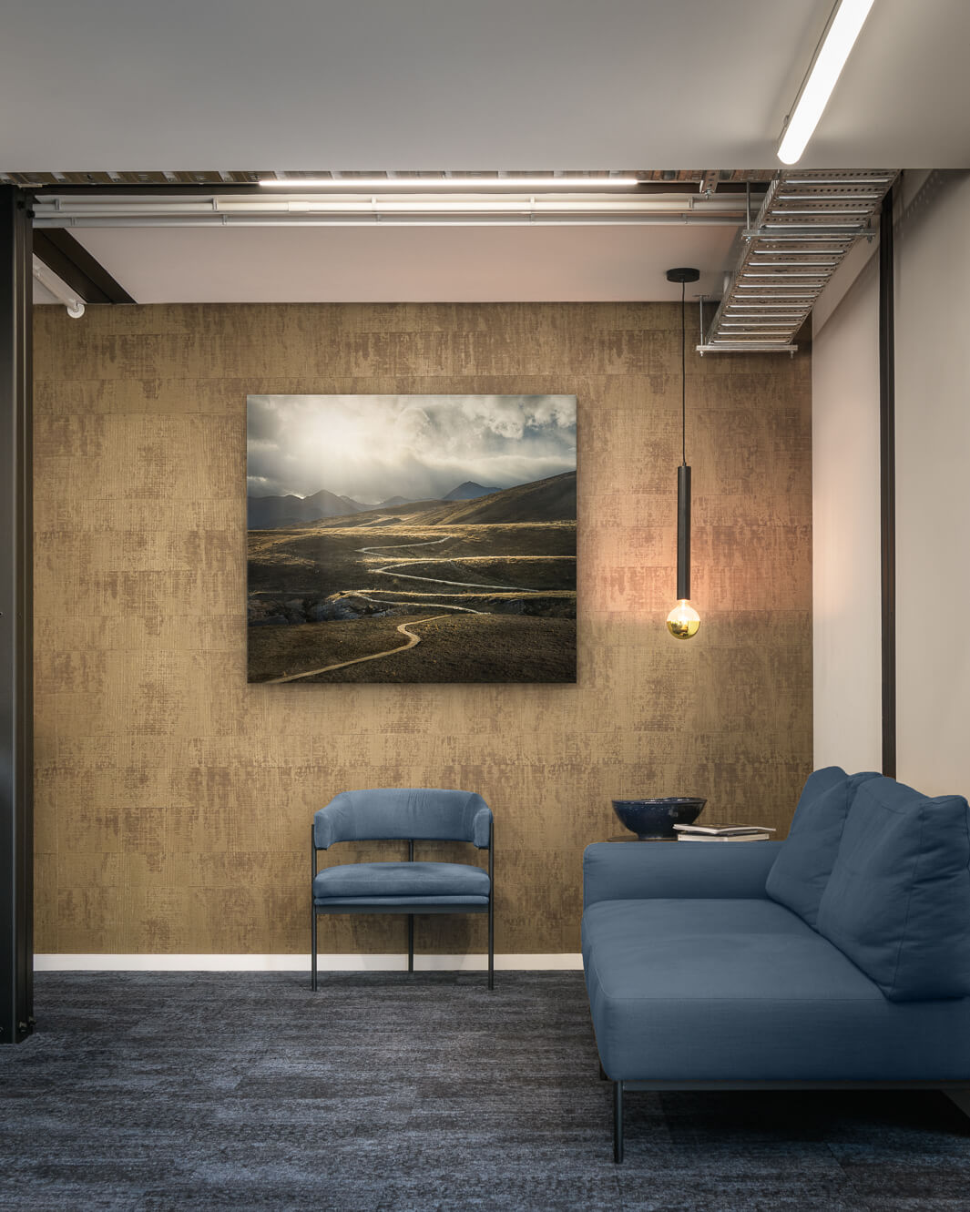 Canvas photo of New Zealand landscape on the wall of an industrial office with couch, chair and pendant light.
