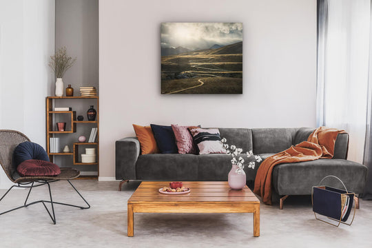 Canvas wall art of landscape photo print with a grey couch, plant, chair and table.