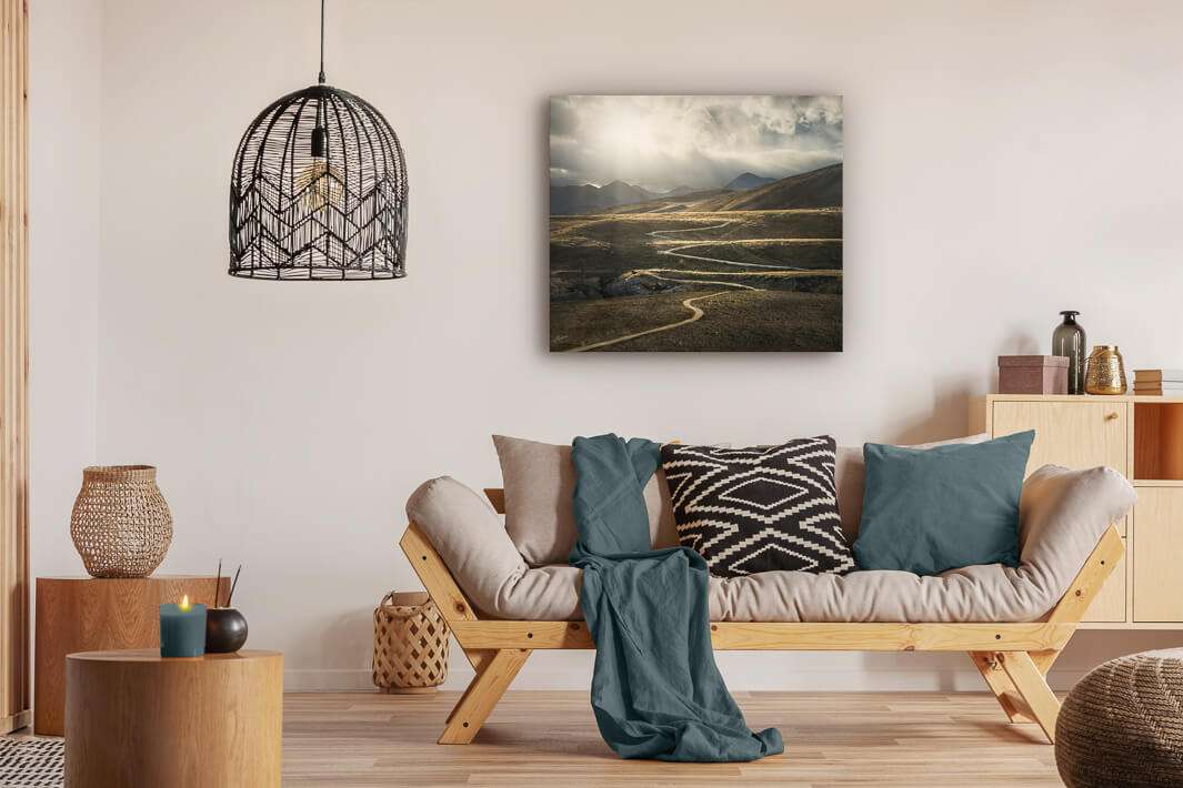 Canvas photo wall art of New Zealand landscape canvas print in lounge setting with a couch, cushions, coffee tables, and pendant light.