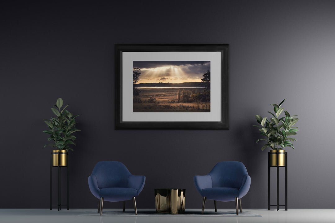 New Zealand landscape framed photo print on a dark wall with two blue chairs and two pot plants
