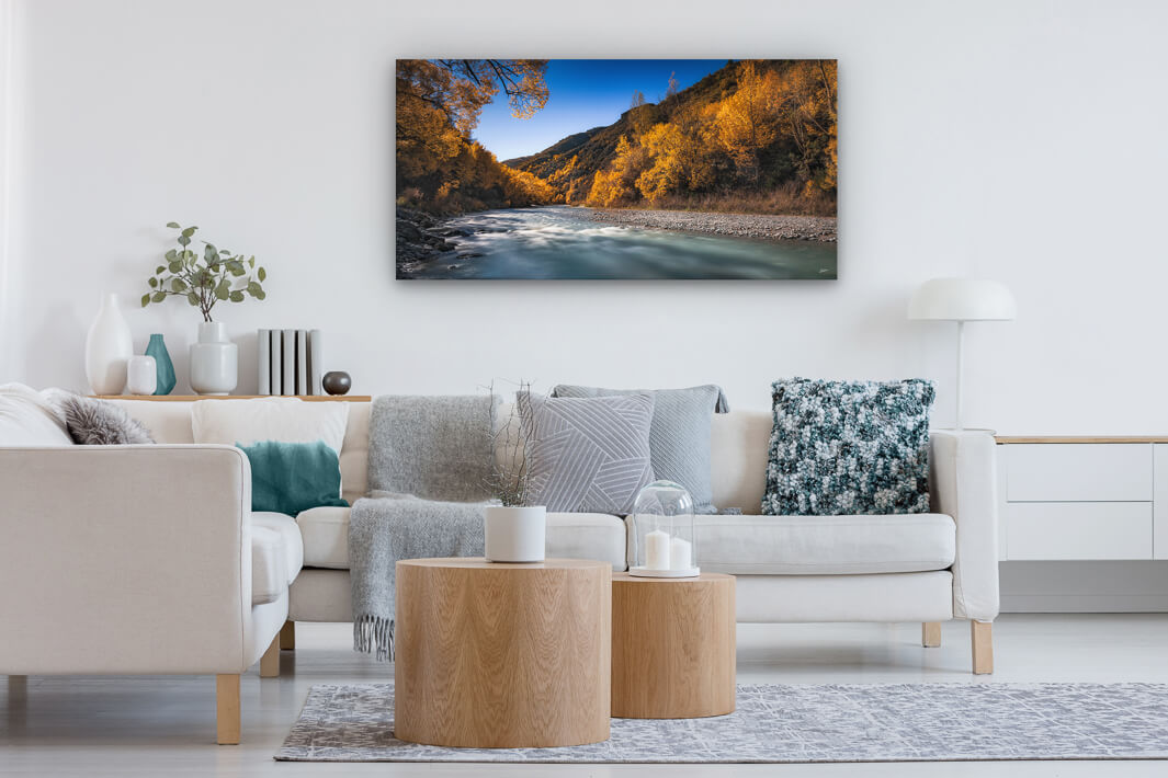 Panoramic photo hung on a lounge wall, showing the Arrow River in Arrowtown during autumn.