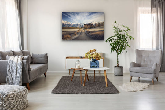 Canvas wall art of landscape photo print with a grey couch, plant, chair and table.