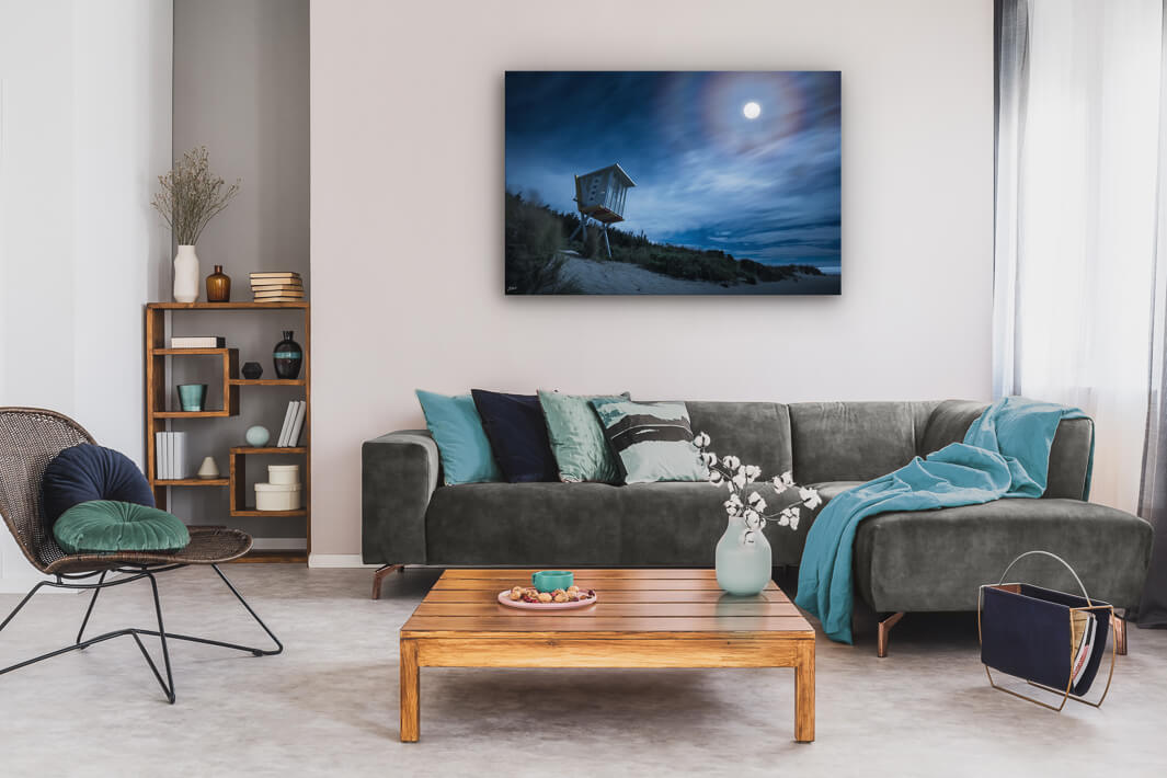 Canvas wall art of landscape photo print with a grey couch, plant, chair and table.