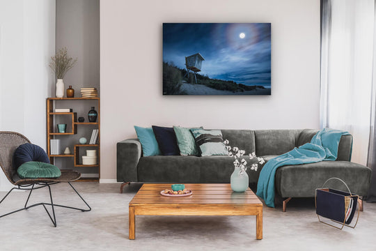 Canvas wall art of landscape photo print with a grey couch, plant, chair and table.