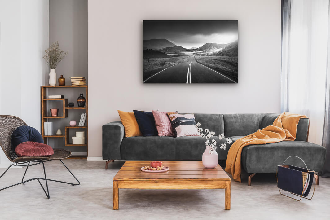 Canvas wall art of landscape photo print with a grey couch, plant, chair and table.