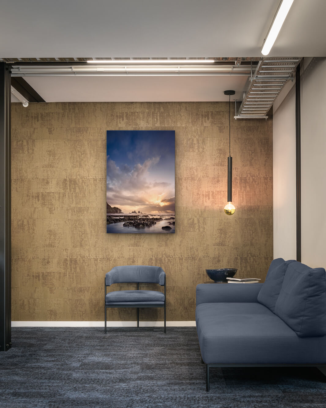 Canvas photo of New Zealand landscape on the wall of an industrial office with couch, chair and pendant light.