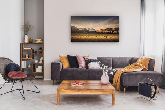 Canvas wall art of landscape photo print with a grey couch, plant, chair and table.