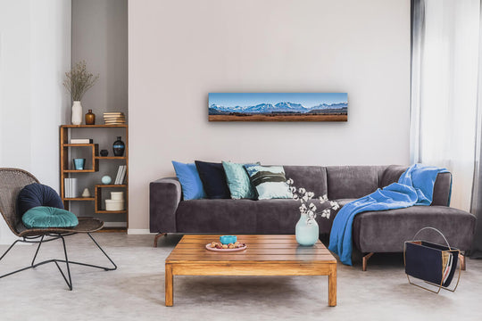 Canvas wall art of landscape photo print with a grey couch, plant, chair and table.