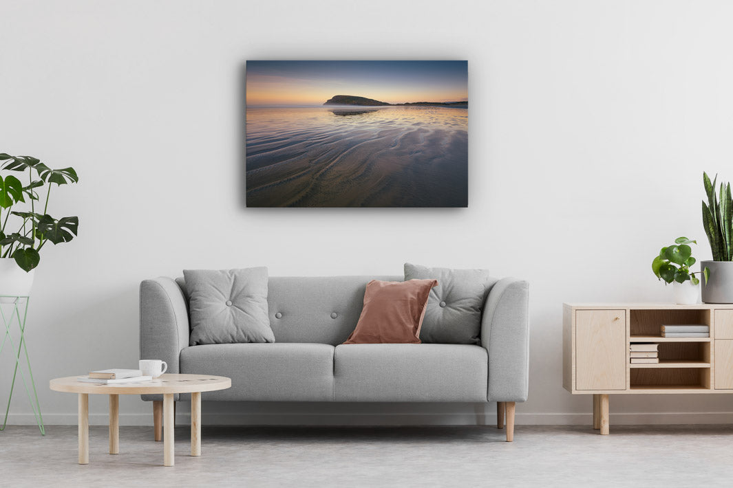 Canvas wall art of landscape photo print with a grey couch, plant, chair and table.
