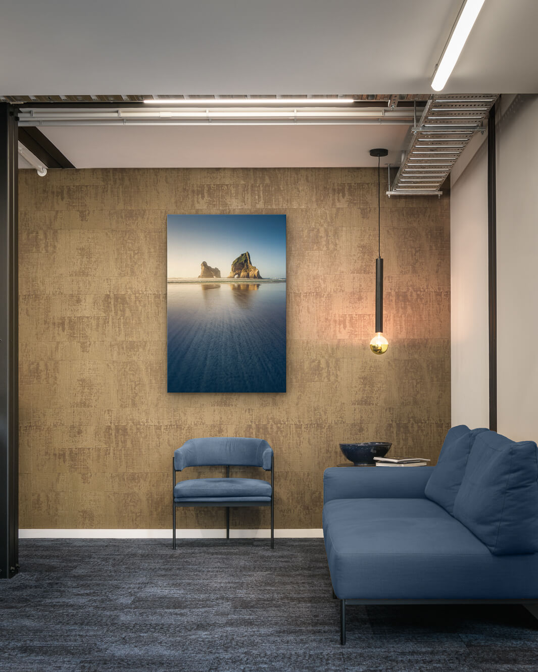 Canvas photo of New Zealand landscape on the wall of an industrial office with couch, chair and pendant light.