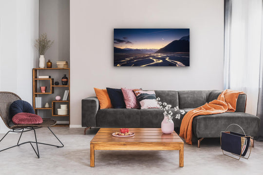 Canvas wall art of landscape photo print with a grey couch, plant, chair and table.