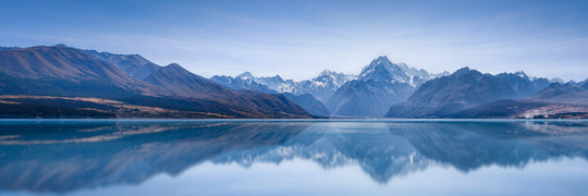 Panoramic landscape photo of Aoraki Mount Cook, New Zealand's highest mountain, reflected in the blue water of Lake Pukaki