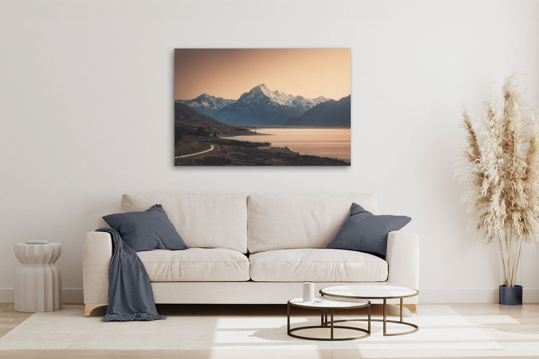 Mountain photo wall art in neutral lounge setting with a white couch, cushions, coffee tables and plant
