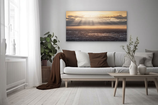 Landscape photo wall art in neutral lounge setting with a white couch, cushions, coffee tables and plant