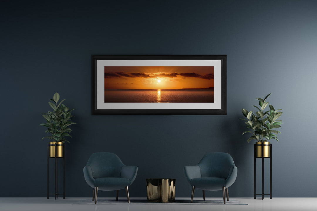 Framed photo of New Zealand landscape print on a dark wall with chairs and pot plants