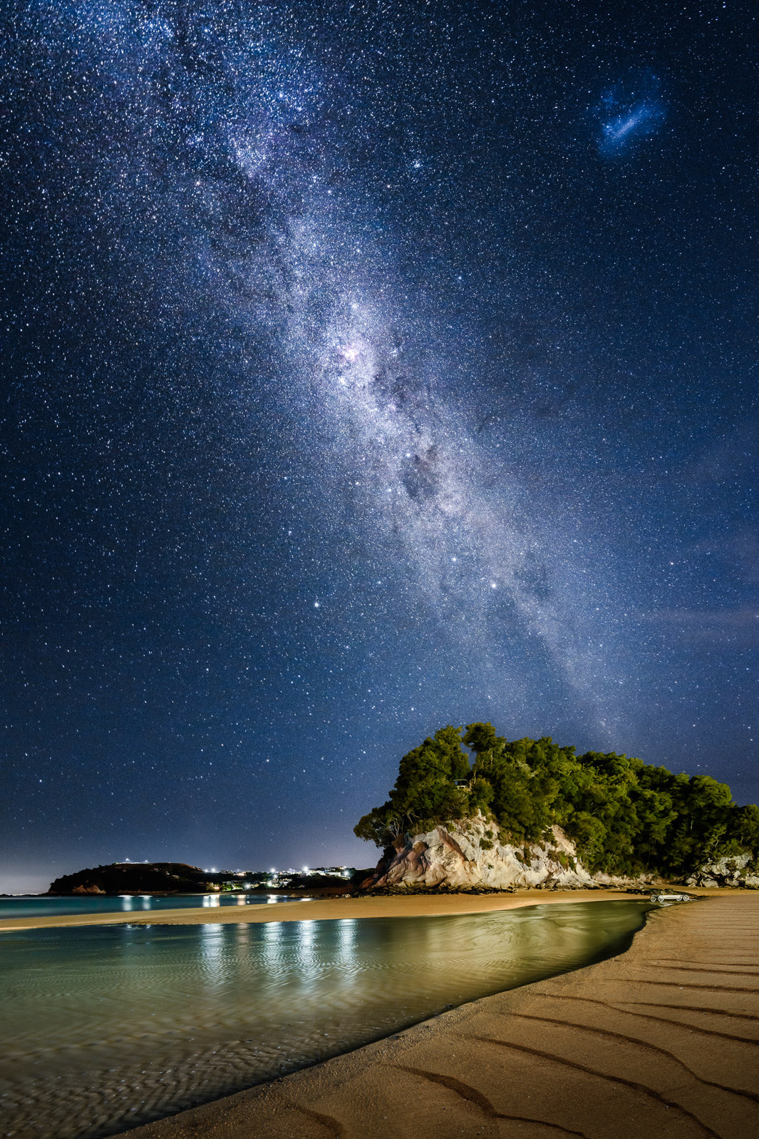 Long exposure astrophotography of Milky Way over rocks and beach in Kaiteriteri, New Zealand.