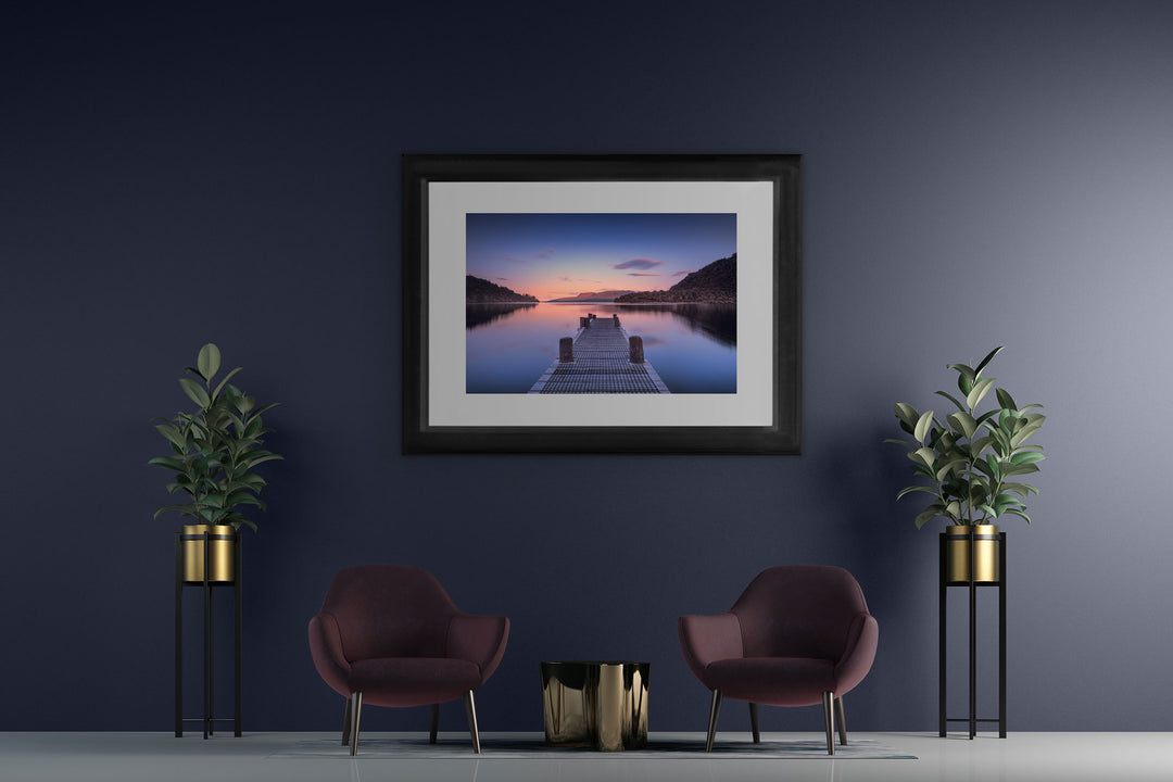 New Zealand landscape framed photo print on a dark wall with two blue chairs and two pot plants