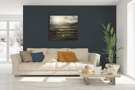New Zealand landscape canvas photo wall art in lounge setting with a dark wall, white couch, coffee table, plant, cushions