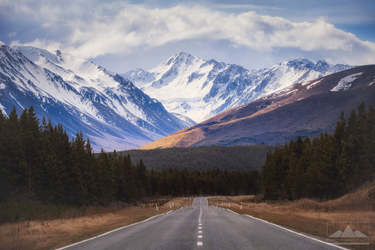 New Zealand country road leading to snowy mountains