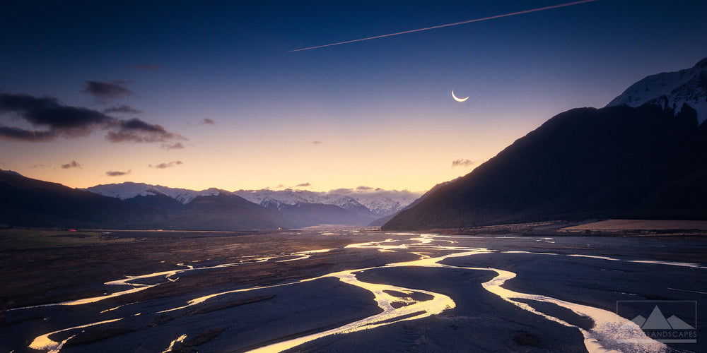 landscape photo of a valley, streams and mountain at night with a crescent moon in the sky