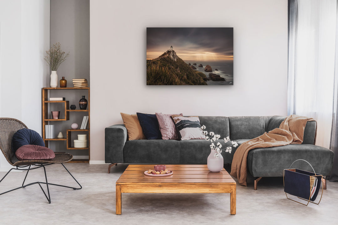 New Zealand landscape photo canvas wall art in neutral lounge setting with a grey couch, coffee table, chair and bookcase.