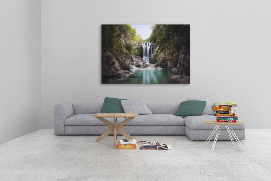 Piroa Falls print above a grey couch on a light wall, showcasing the serene waterfall scene in a bright and minimalist interior.