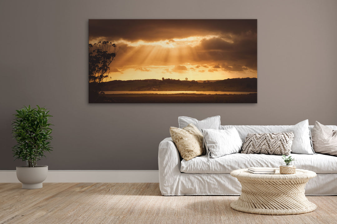 New Zealand landscape canvas photo wall art in lounge setting with a brown wall, white couch, coffee table, plant, cushions