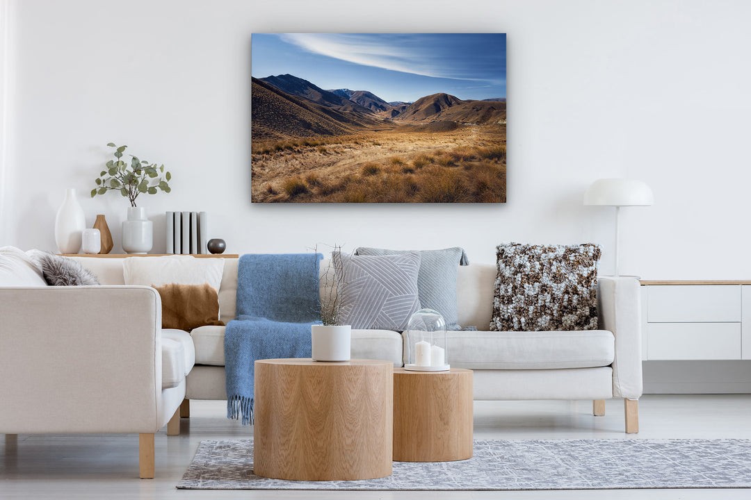 Image contains a photo print on the wall of a contemporary lounge with couches, cushions and coffee table.