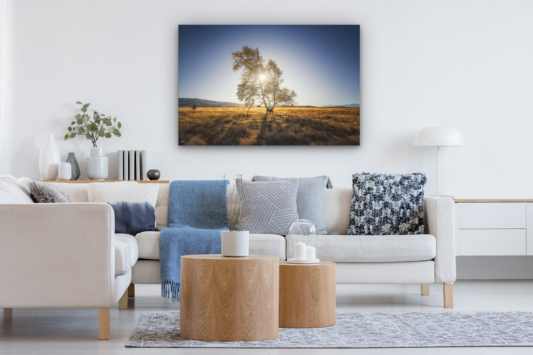 New Zealand landscape photo canvas wall art in neutral lounge setting with a white couch, coffee tables, rug and books