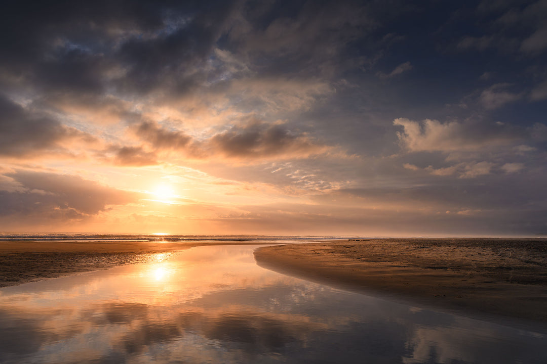 Morning sun in the blue sky with clouds that are reflected below in the sand stream.