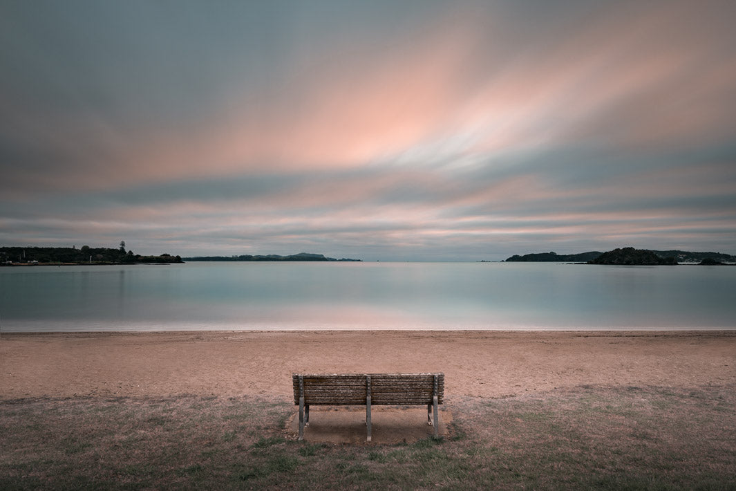 photo scene of a bench seat on the beach in Paihia, Bay of Islands at sunset