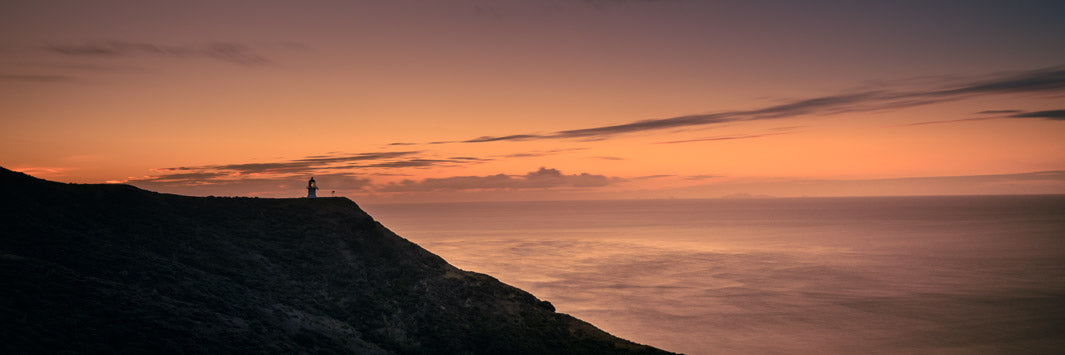 Panorama landscape photo print of the lighthouse in silhouette at Cape Reinga at sunset.
