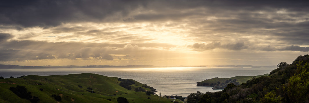 Panoramic sweeping views from the Coromandel hills to Waiheke Island, with the sun beaming through the clouds.