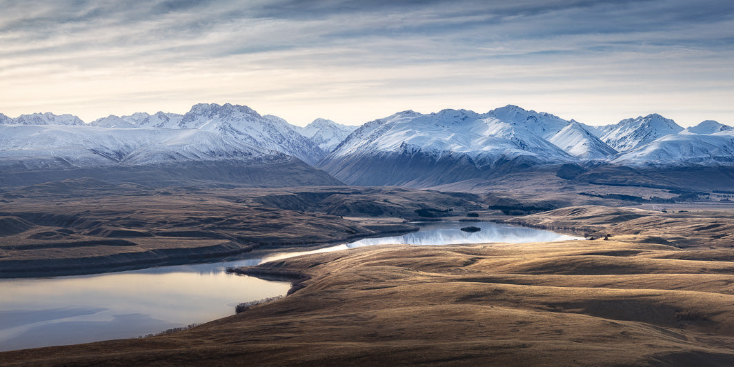 Lake Alexandrina surrounded by brown, earthy hills and snow capped mountains in the background