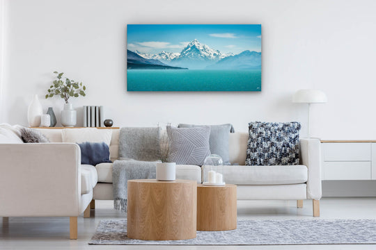 Blue toned photo print of Aoraki Mt Cook on the wall of a lounge with neutral decor.