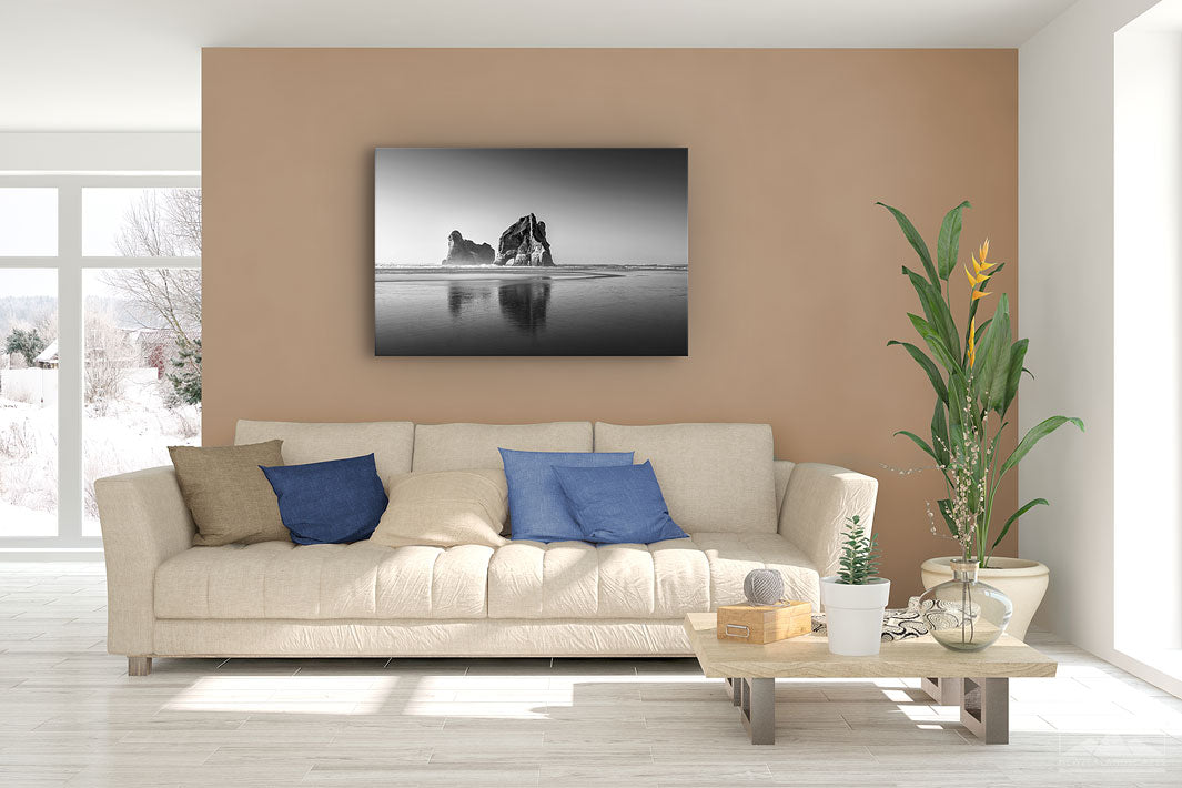 Fine art black and white canvas print showing the Archway Island rocks at Wharariki Beach, displayed on a lounge room wall