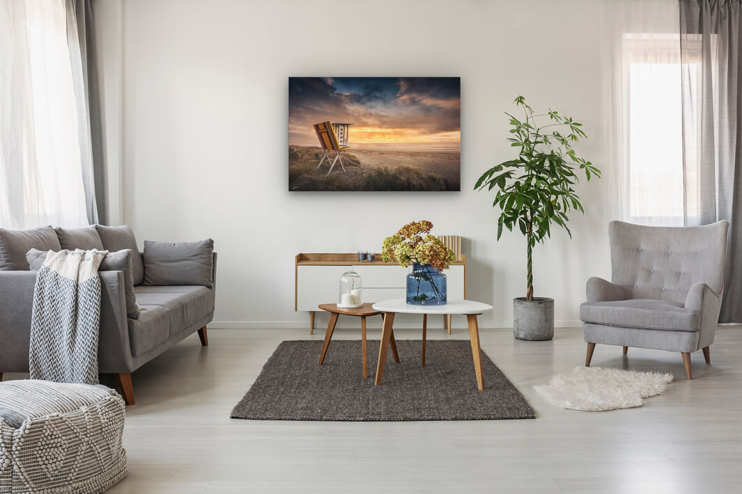 Beach in New Zealand photo wall art in neutral lounge setting with a couch, rug, plant, flowers, chair and curtains