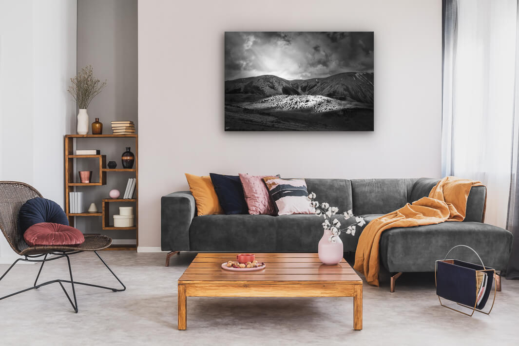 Canvas wall art of landscape photo print with a grey couch, plant, chair and table.