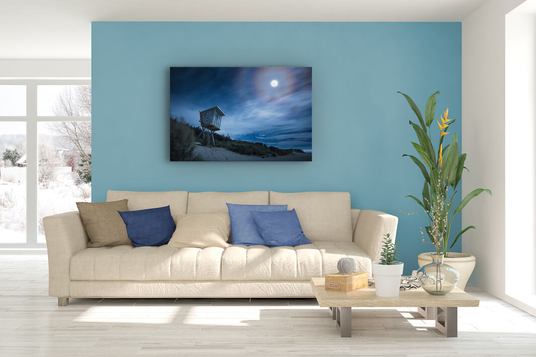 New Zealand landscape photo canvas wall art in lounge setting with blue wall, a white couch, cushions, coffee table and plant