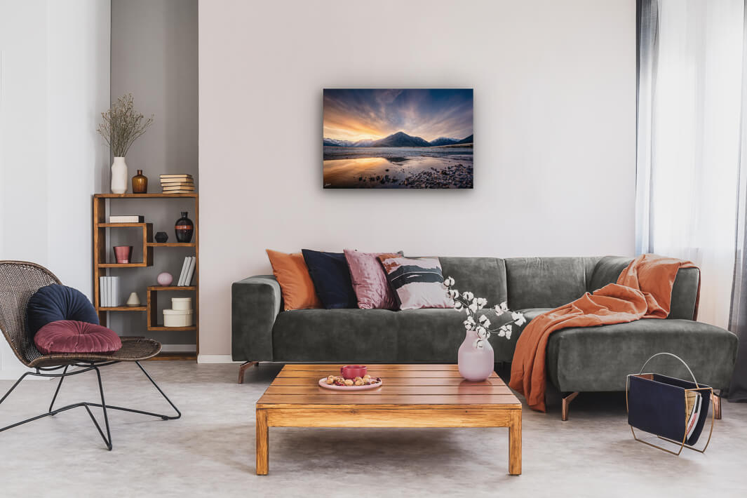 Canvas wall art of landscape photo print with a grey couch, plant, chair and table.