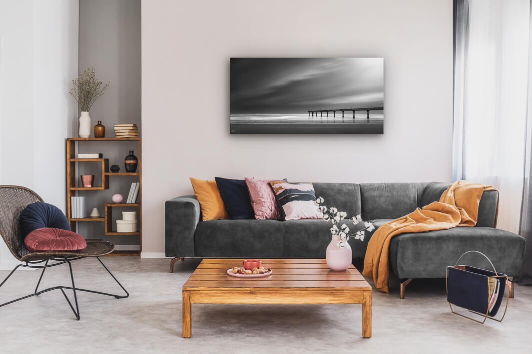 Canvas wall art of landscape photo print with a grey couch, plant, chair and table.