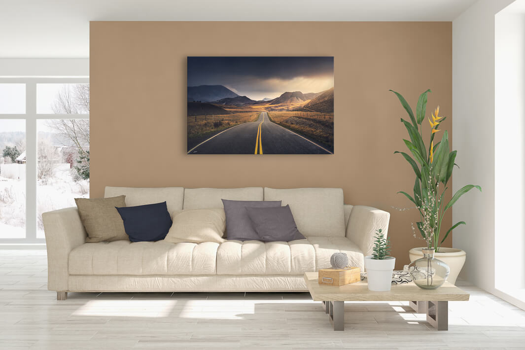 New Zealand landscape canvas photo wall art in lounge setting with a beige wall, white couch, coffee table, plant, cushions