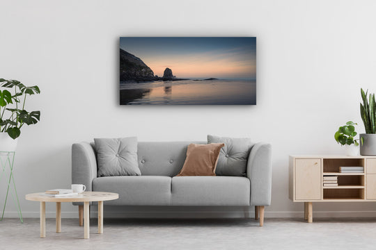 Plants, sofa, coffee table and cabinet in a room with a panoramic wall print of the sea at sunrise.