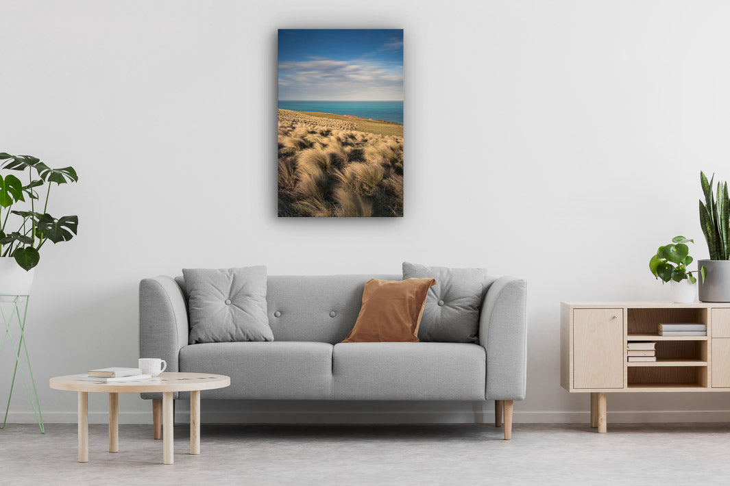 Canvas wall art of landscape photo print with a grey couch, plant, chair and table.