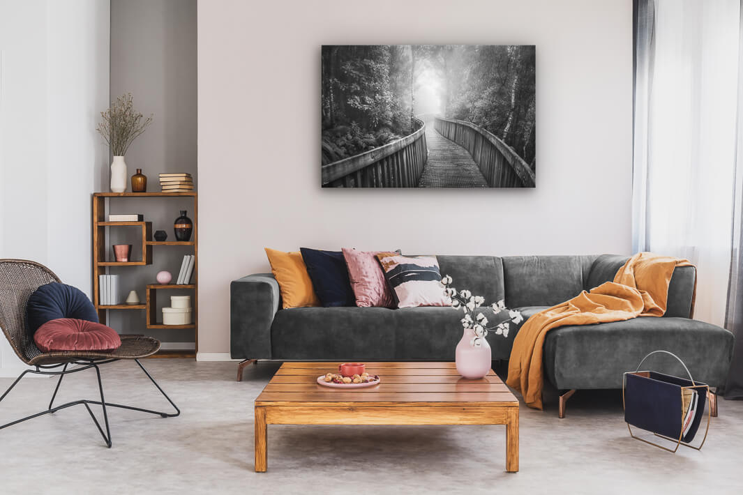 Canvas wall art of landscape photo print with a grey couch, plant, chair and table.