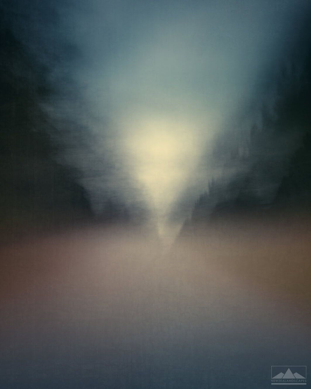 Abstract impressionist style blurred photo of a road inbetween trees, with sky and sunlight in the distance.