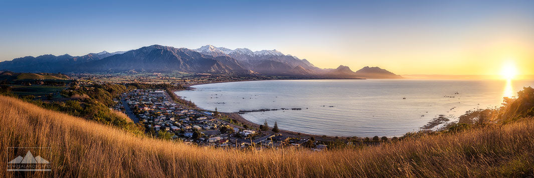 Panoramic view of Kaikoura from a lookout, with sea, mountains and township in the distance.