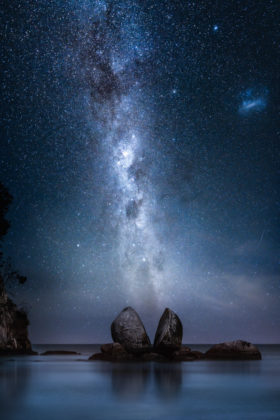 Night time astrophotography of the Milky Way and stars in the sky above Split Apple Rock, famous in New Zealand