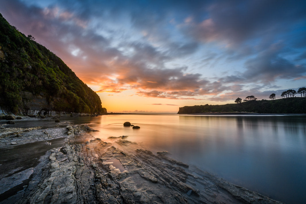 Sunset at Tongaporutu and the Three Sisters in Taranaki. Rocks leading in to hills and trees alongside the river.