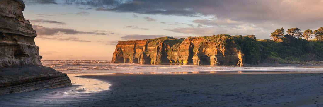 Photo taken at dusk at the Tongaporutu river mouth in New Zealand's Taranaki region. Rocks and trees in the background.